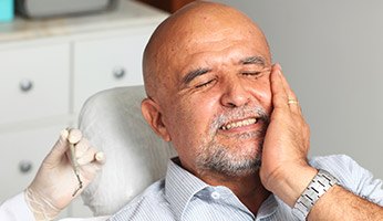 Man in dental chair holding jaw